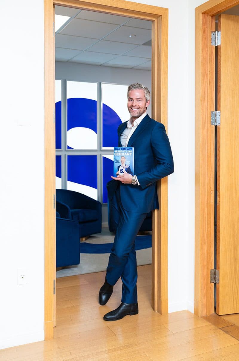 Ryan Serhant holding BRAND IT LIKE SERHANT book